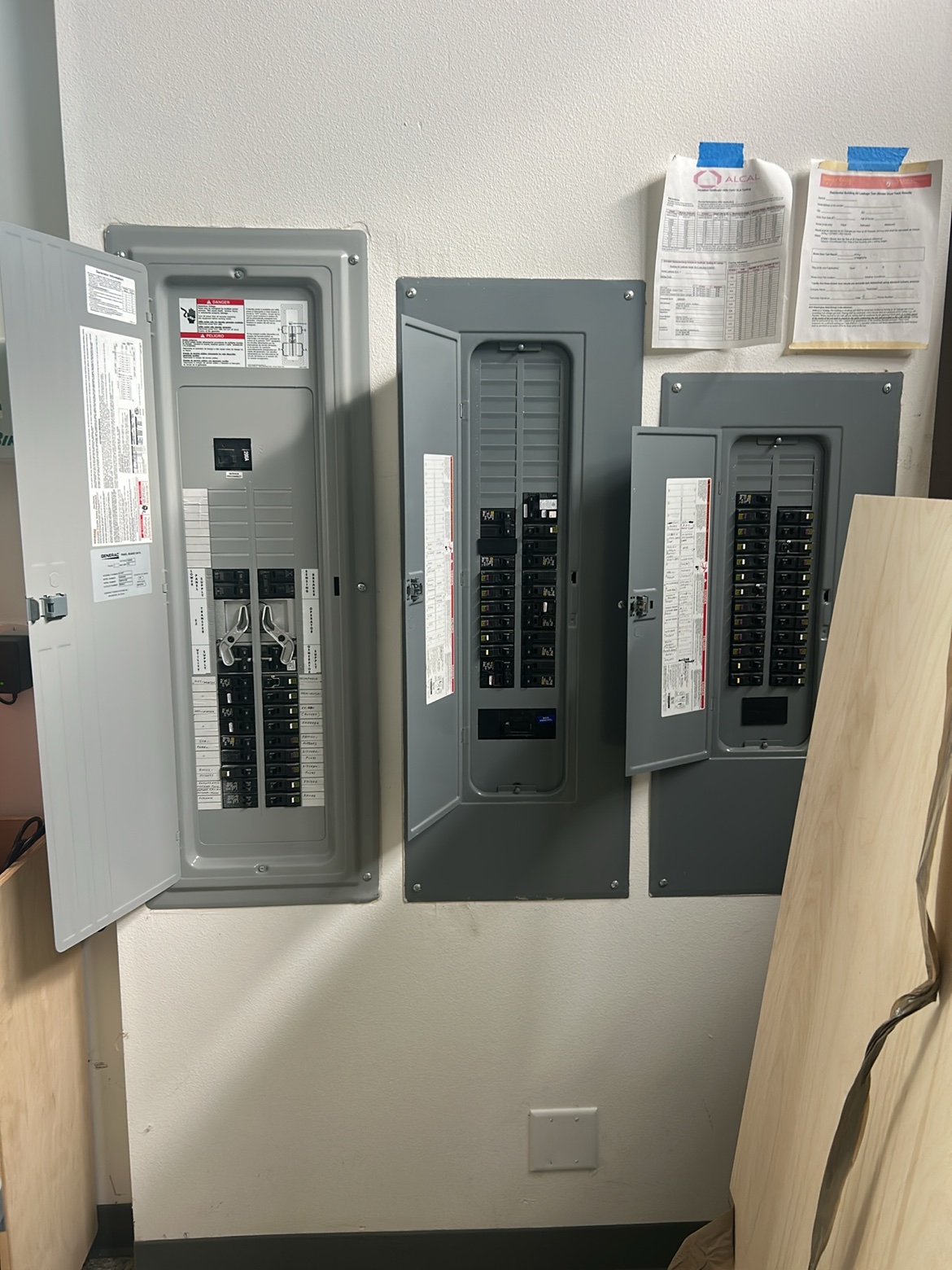 Three electrical panels side by side including a Generac transfer panel installed by Washington Electrical
