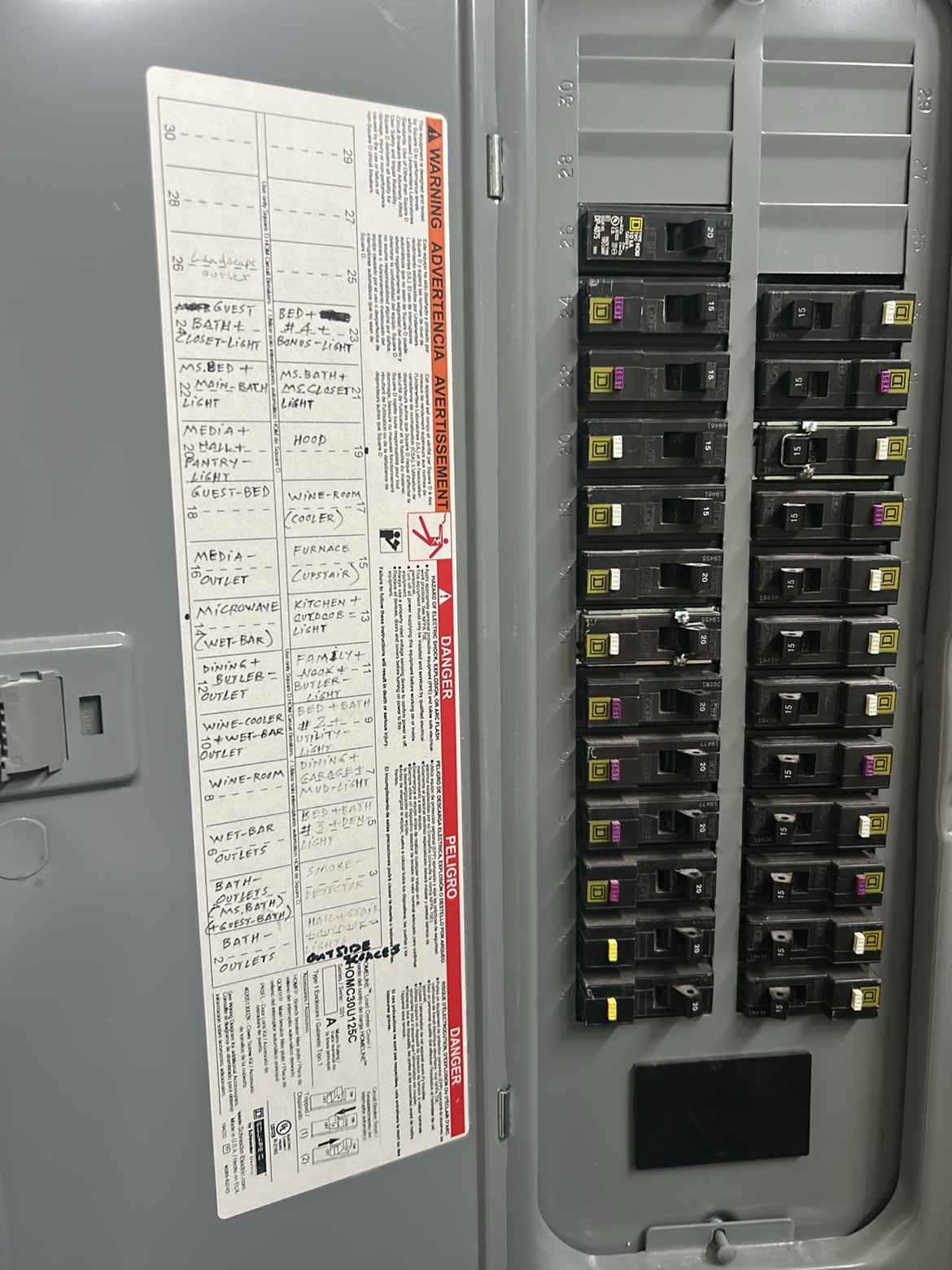 Electrical panel interior with a neatly hand-labeled circuit directory by Washington Electrical